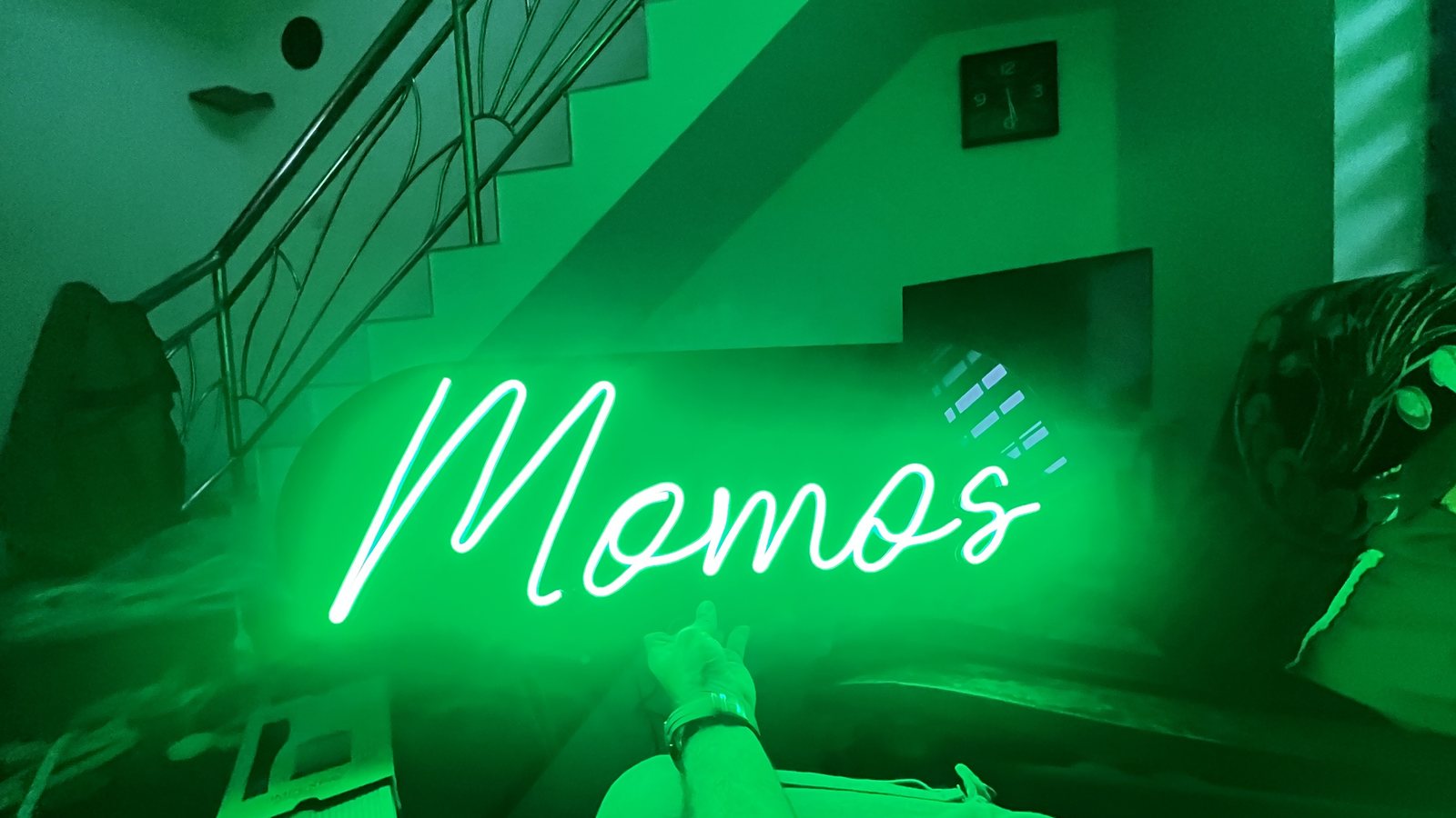 Green Momos neon sign on staircase wall