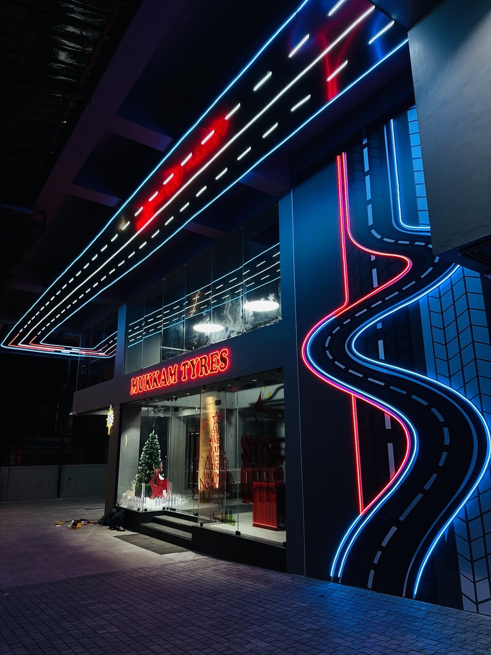 Mukkam Tyres storefront with red signage and blue architectural LED feature